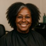 Black woman with natural curls getting a trim, smiling confidently, showcasing healthy vibrant hair